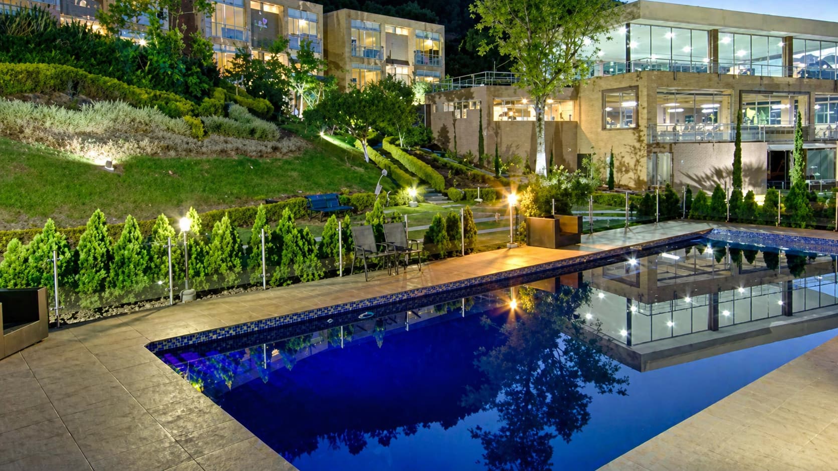 Vista exterior del lugar al atardecer con piscina y jardines